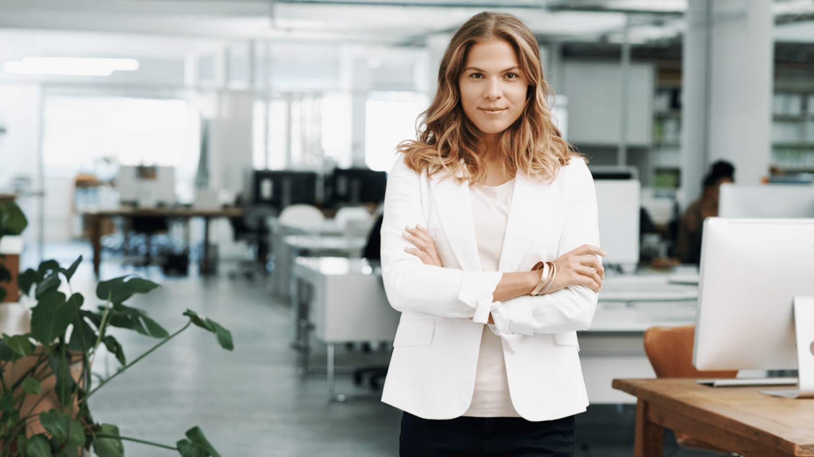 a woman dressed in business attire standing attentively with her arms crossed