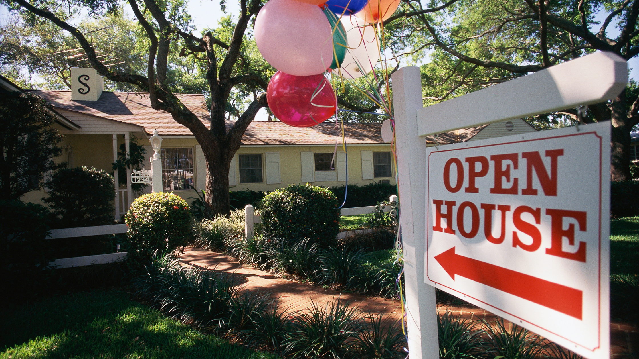 real estate sign advertising an open house with pink and red balloons